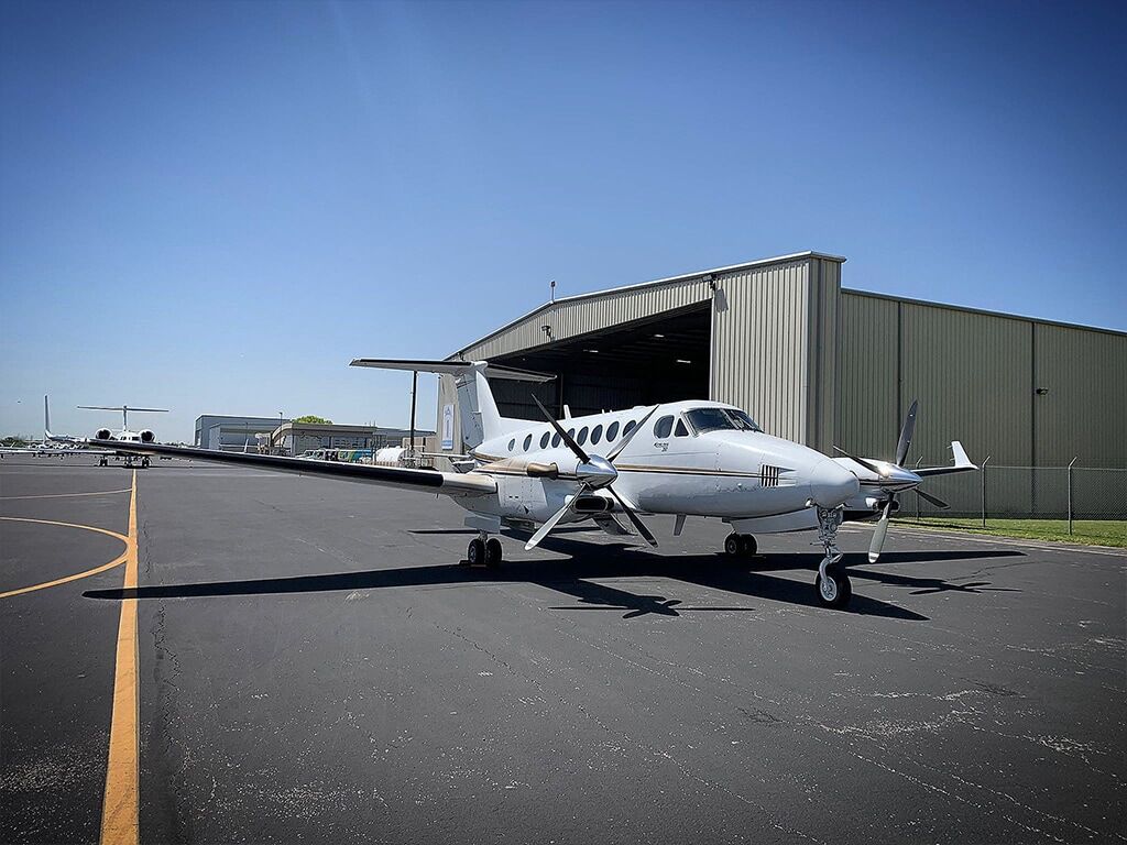 Twin prop airplane in front of hangar