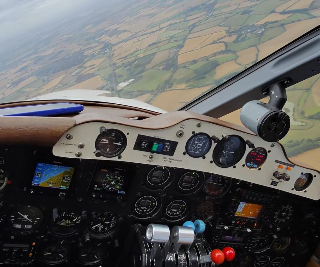 In-flight cockpit view of Aero Commander 500 N711NE with instruments and outside scenery