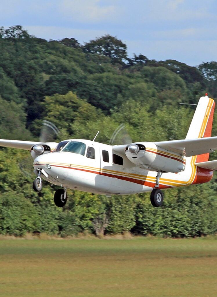 1959 Aero Commander 500A N711NE twin-engine aircraft front view inflight over field